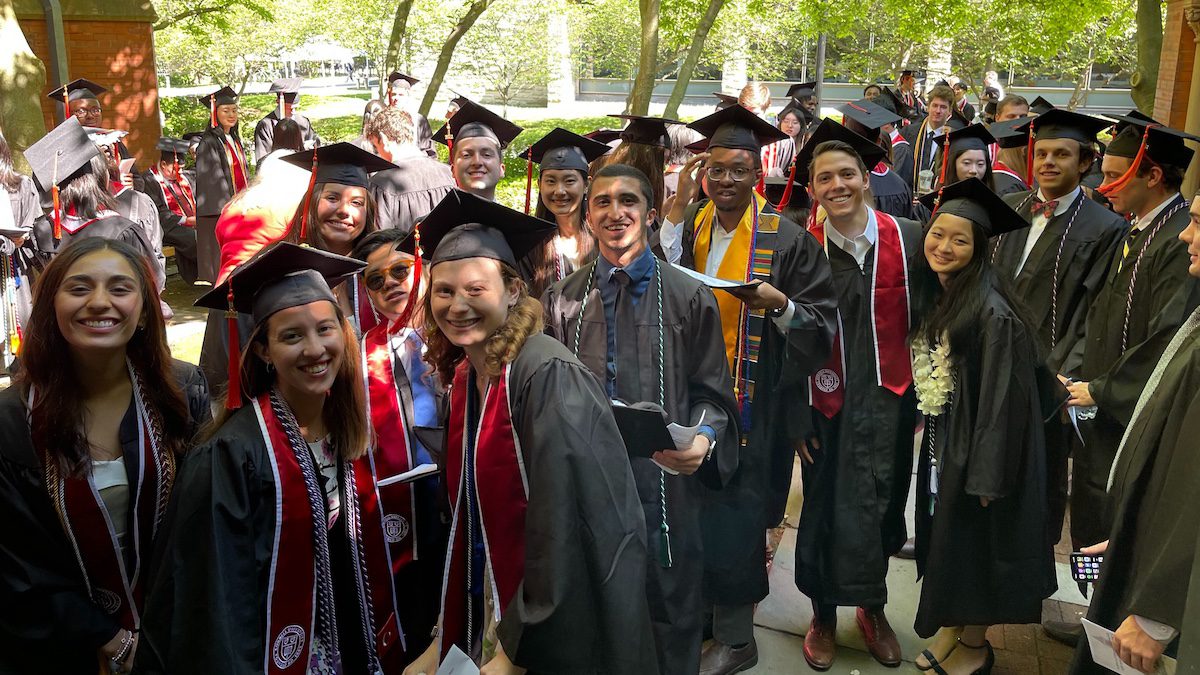ORIE students in caps and gowns smile before entering Sage Chapel for their May 2023 graduation ceremony.