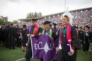 Three Native students at graduation in regalia