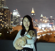 ECE Ph.D. student Danna Ma stands in front of a city skyline at night, holding her cat in her arms