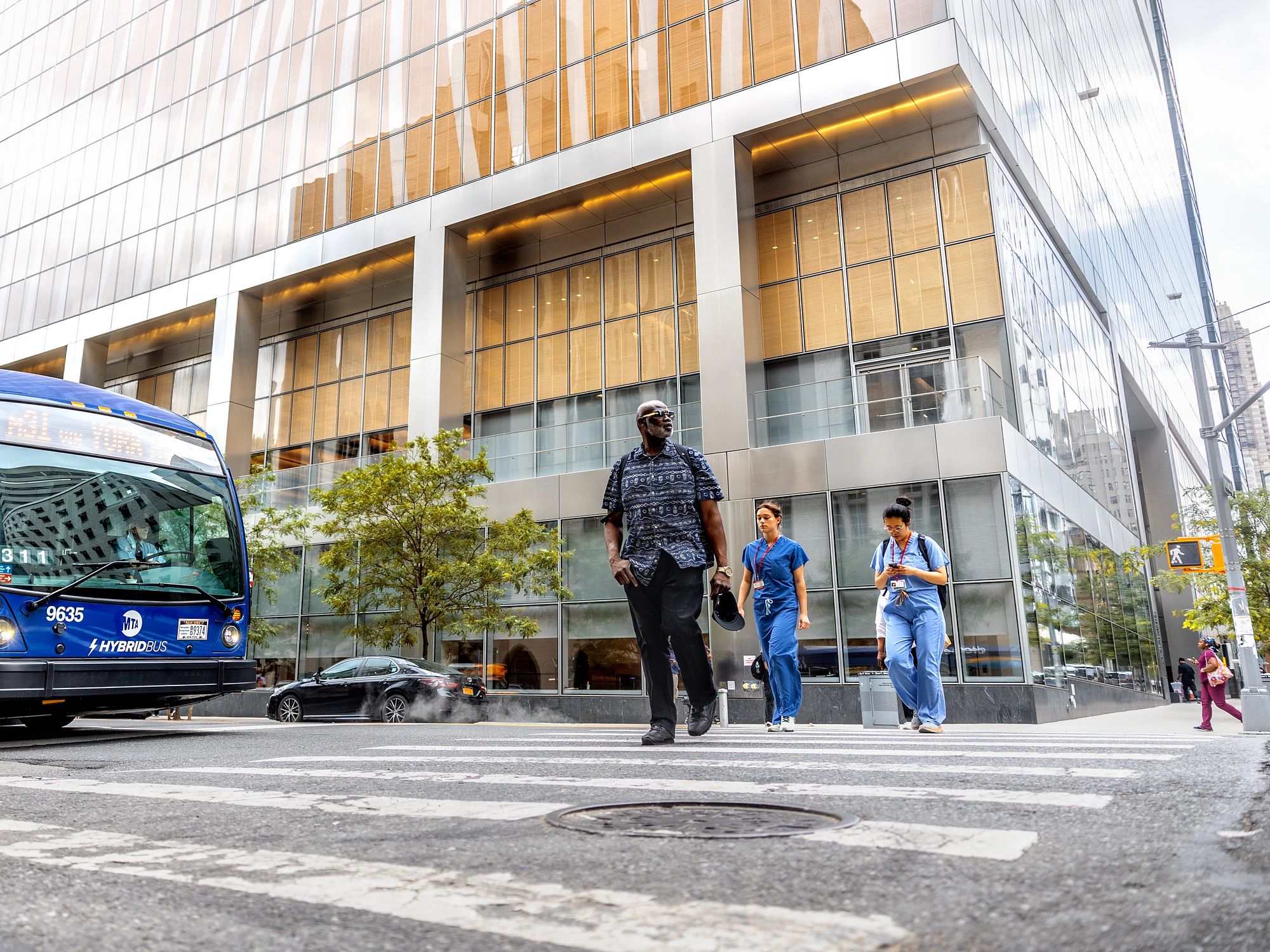 People in medical scrubs walk near Weill Cornell Medicine