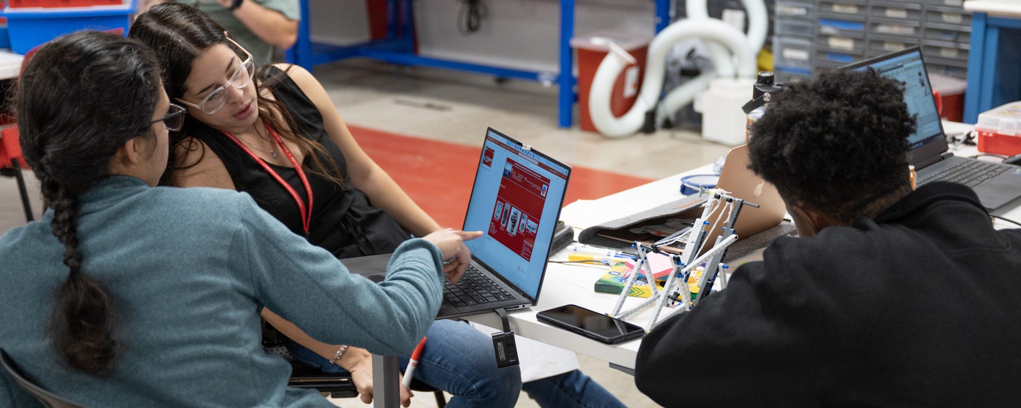 Two students consult with each other while looking at a computer.