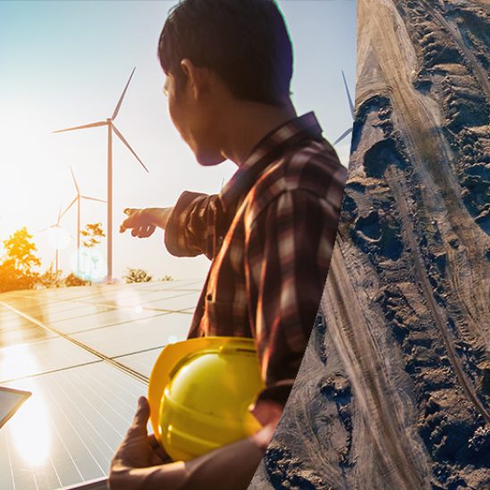 Scientist holding hardhat points toward windmill