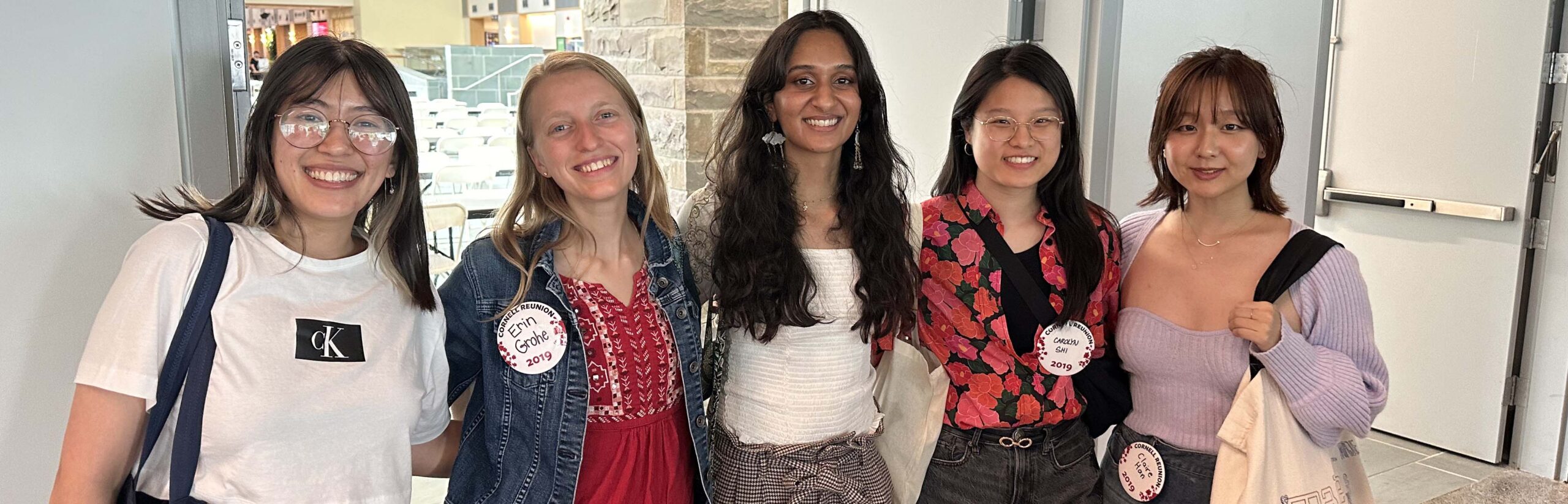 five smiling female student pose with arms behind backs