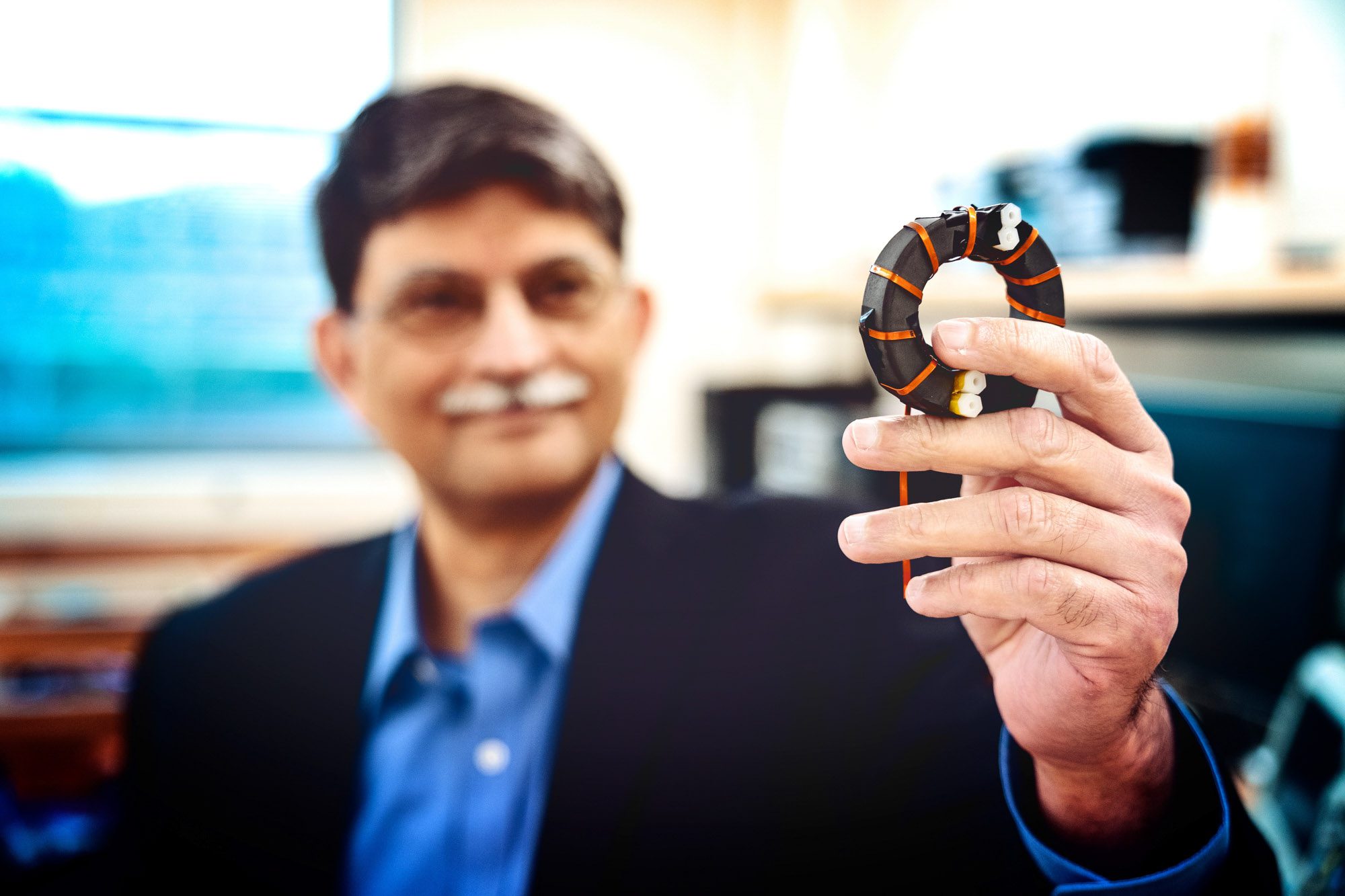 Khurram Afridi in his lab in Phillips Hall holding an inductor.