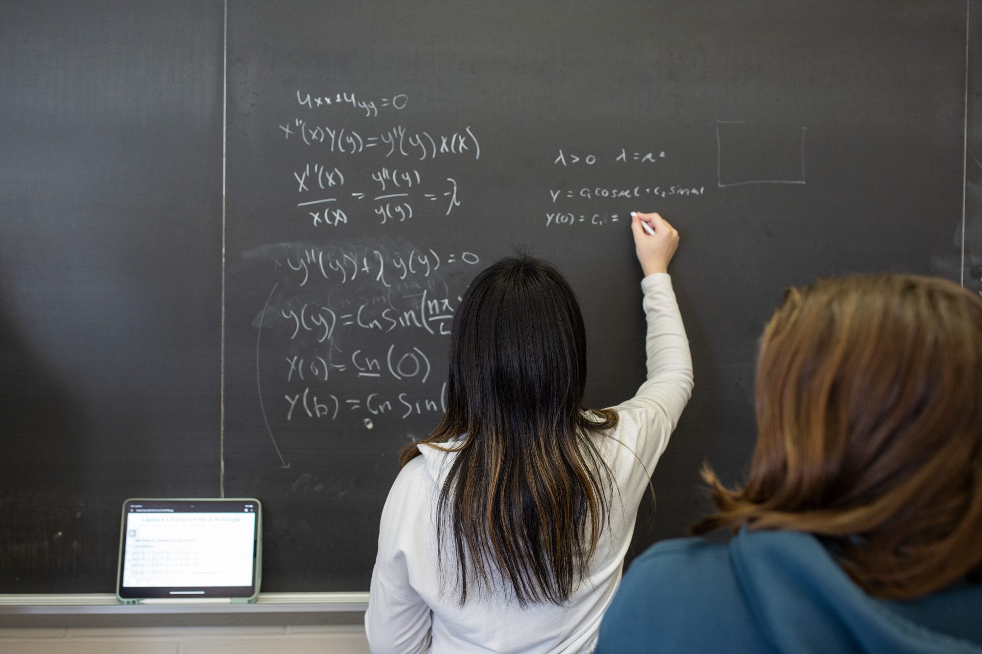 Students work together on equations at a chalkboard during an Academic Excellence Workshop