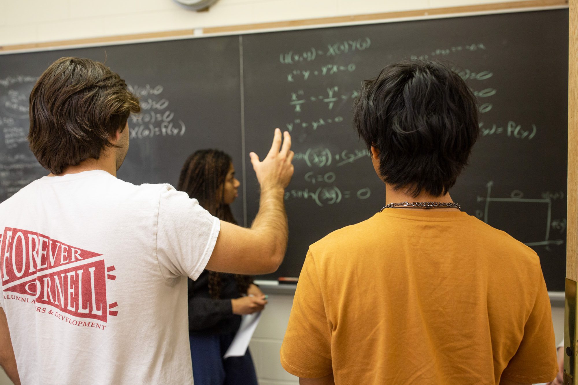 Students work together on equations at a chalkboard during an Academic Excellence Workshop
