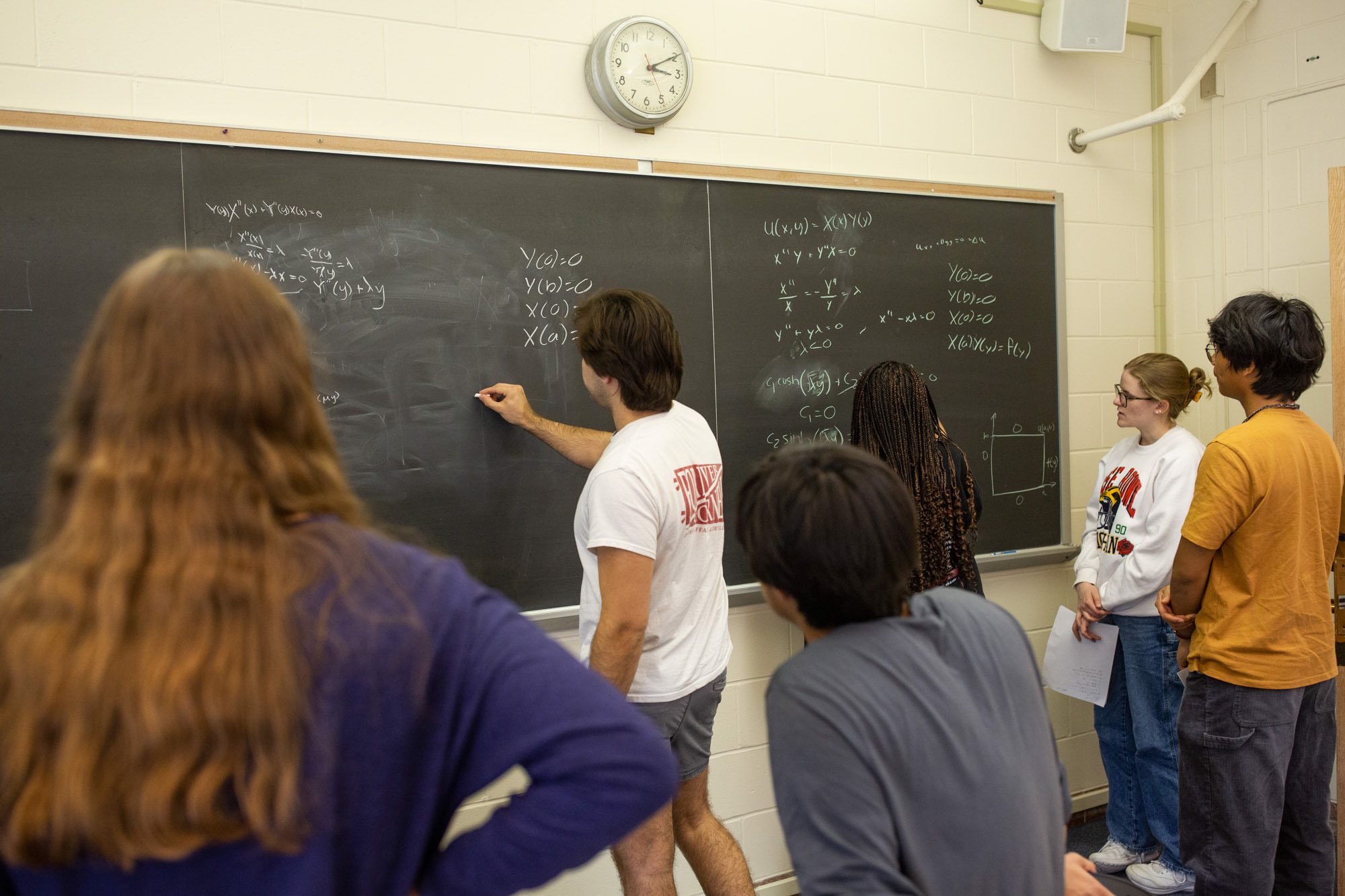 Students work together on equations at a chalkboard during an Academic Excellence Workshop