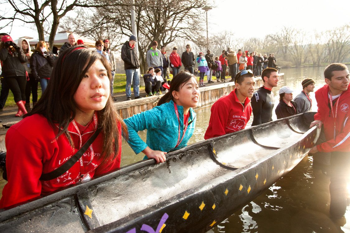 Students carry large canoe into water