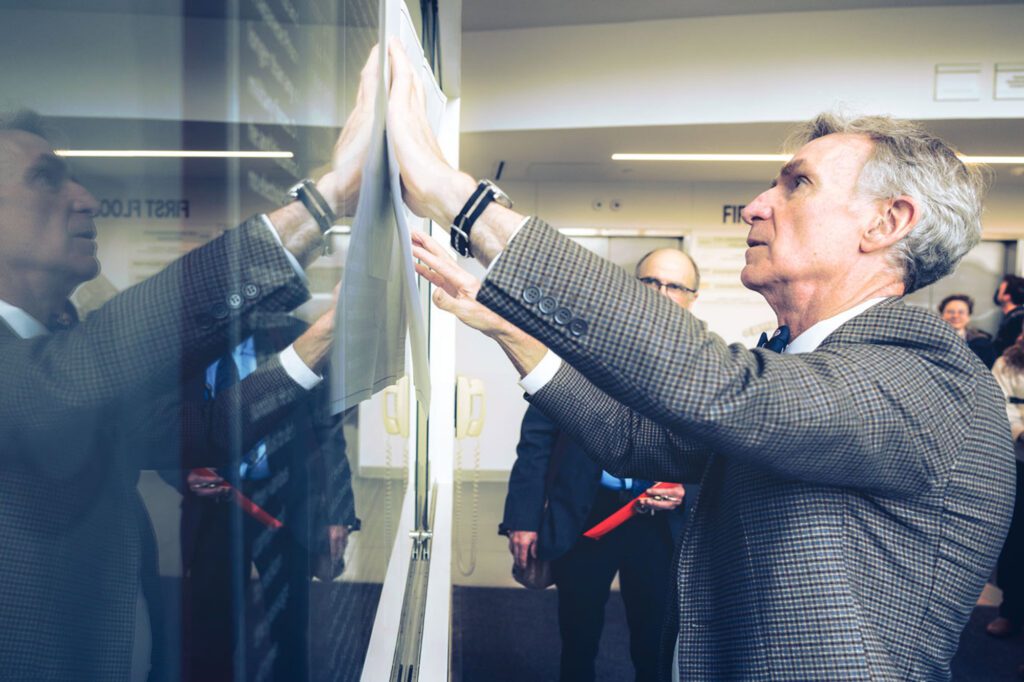 Bill Nye showing solar noon clock projects in front of a screen