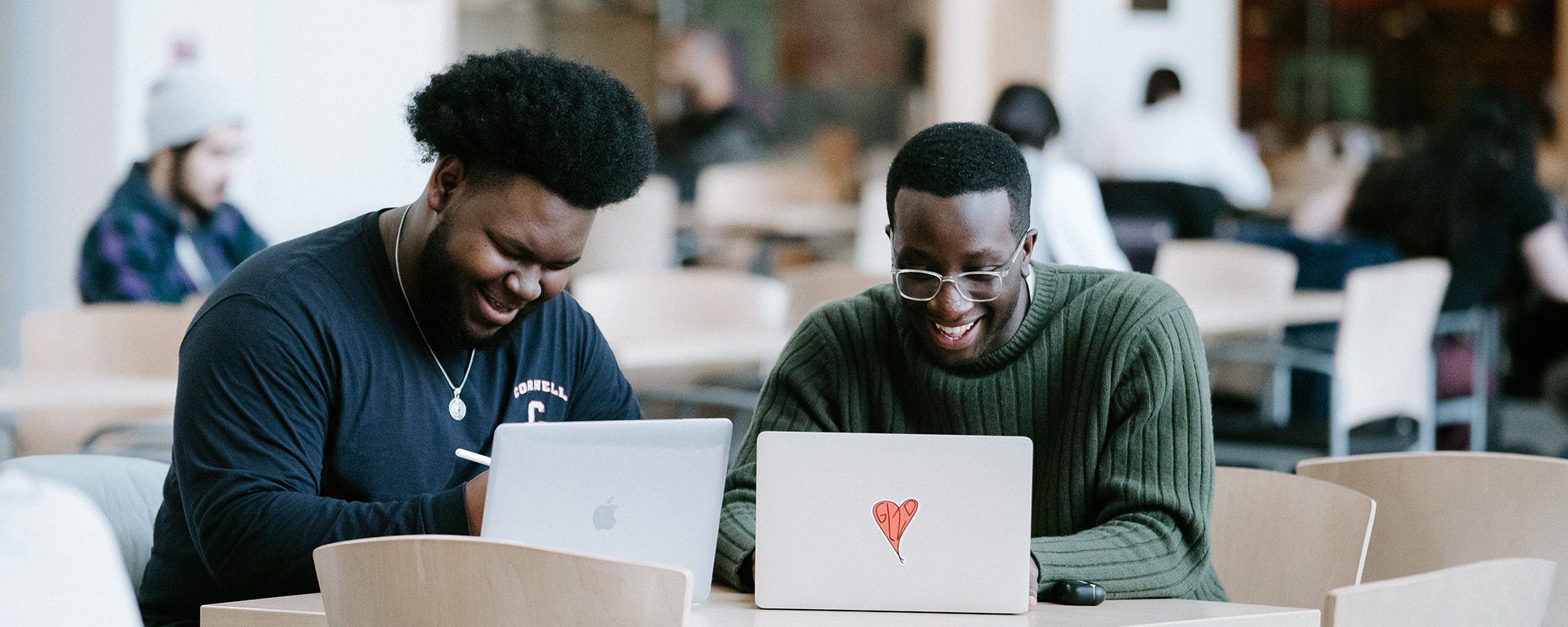 Two students work together on their laptops in Duffield Atrium