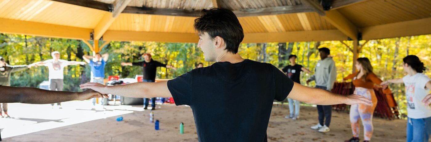 a group of students extend their arms and make a circle