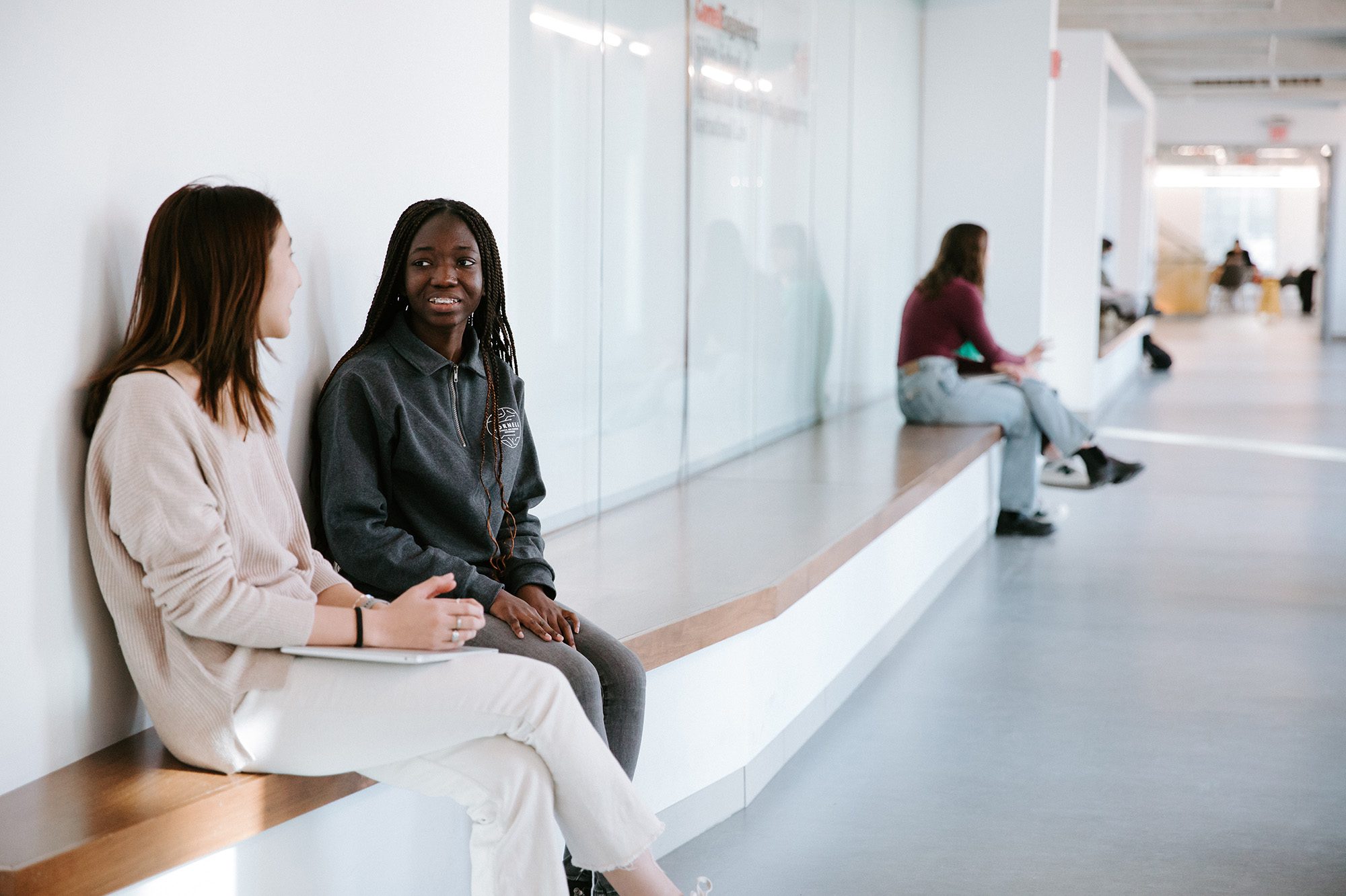 Two students sit and talk on a bench in Upson Hall