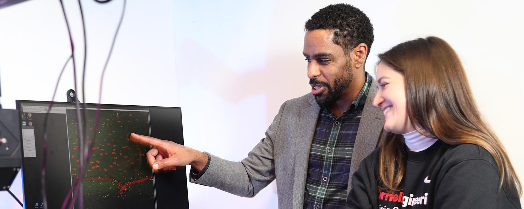 Karl Lewis with student looking at research images on monitor in the lab.