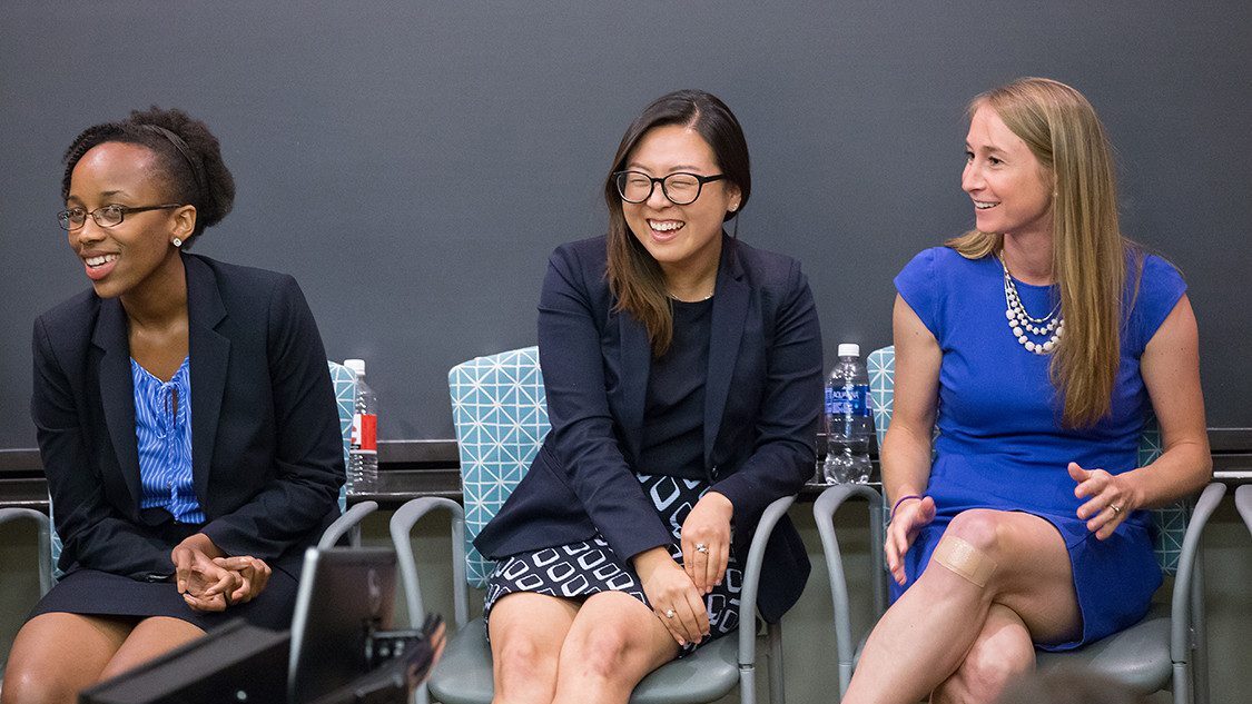 three people smile in chairs