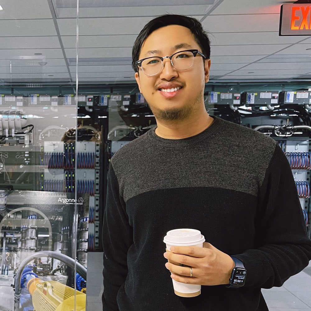 Jian Xun Wang holding a coffee cup standing in a lap