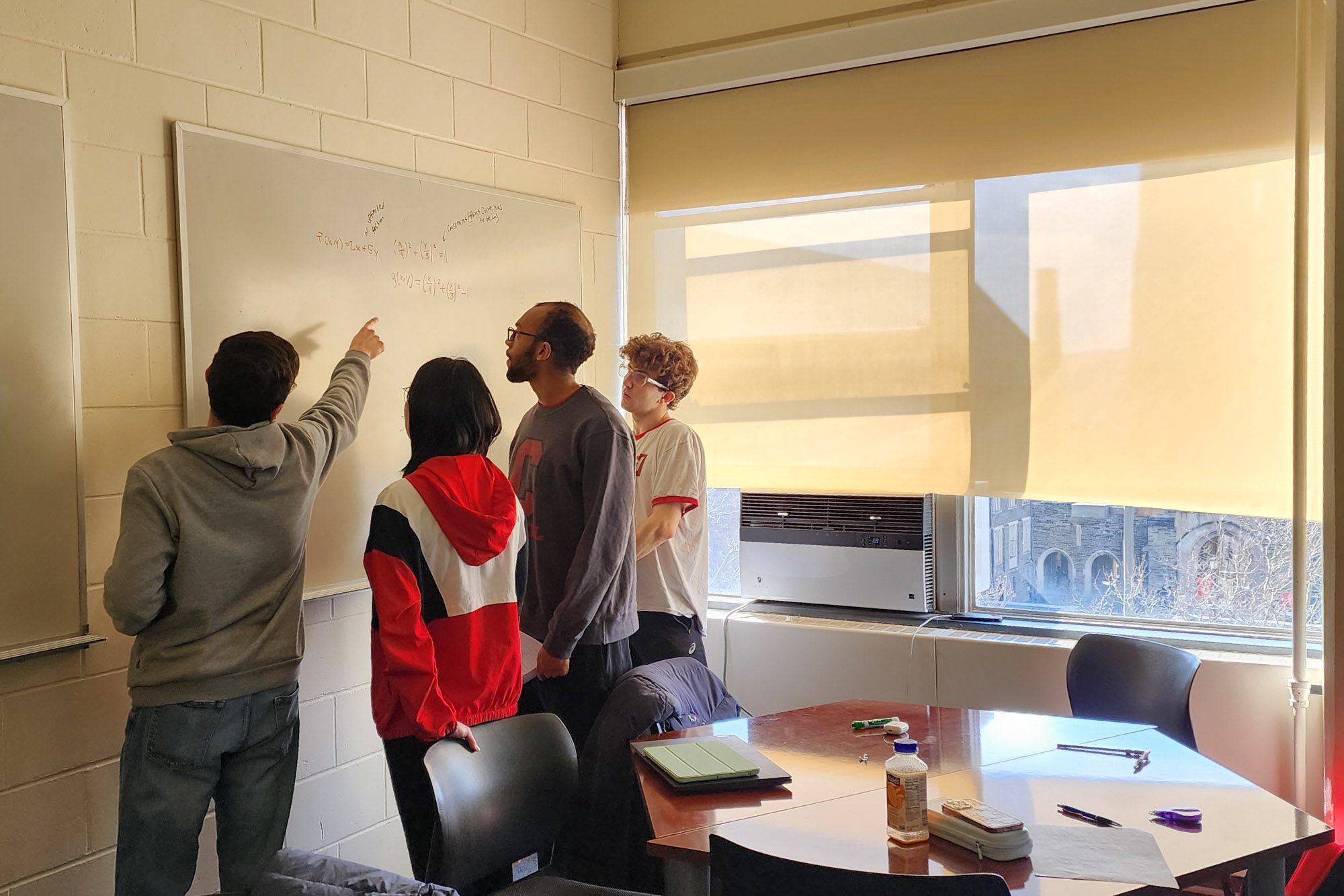 Four students work together at a whiteboard