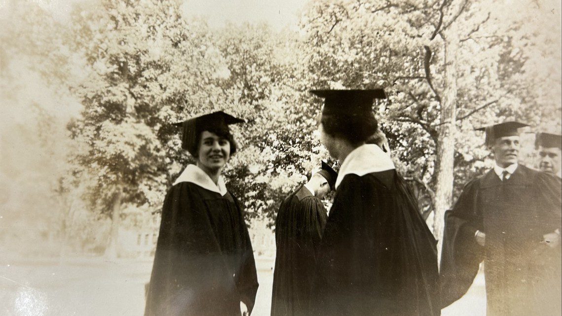 black and white photo of three students in graduation gowns